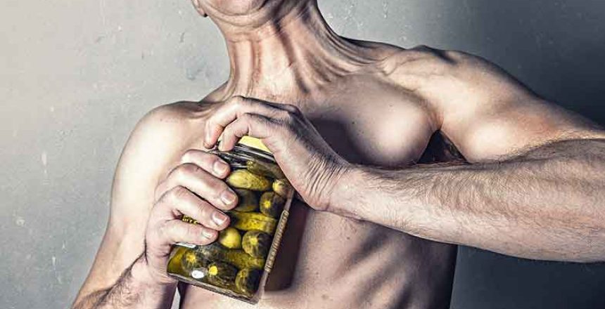 Man trying to open a jar of pickled cucumbers